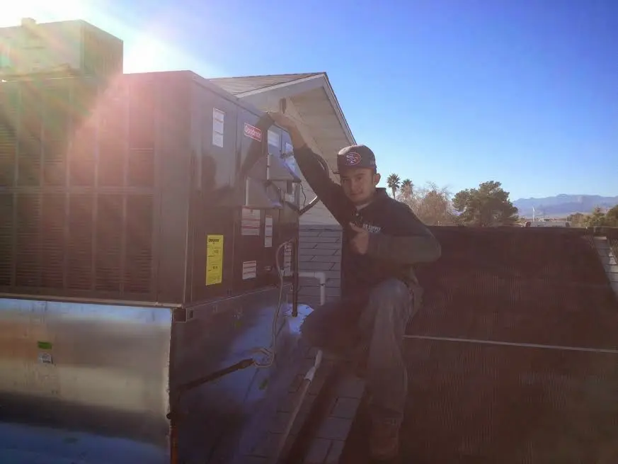HVAC technician performing Air Duct Repair on a rooftop unit in Handy